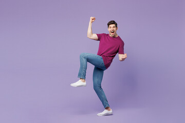 Full body young man wears violet t-shirt casual clothes doing winner gesture celebrate clenching...