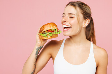 Young overjoyed cool woman wears white top casual clothes hold eat bite burger close eyes isolated...