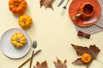 Frame made of beautiful table setting with fresh pumpkins, cinnamon and autumn leaves on yellow background