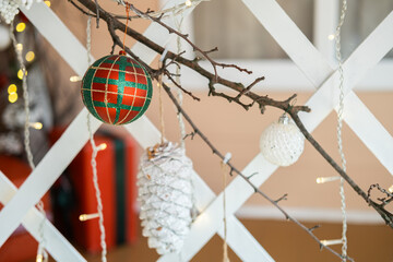 Decorative holiday ornaments hanging on a branch near twinkling lights