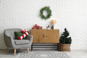 Interior of living room with Christmas tree, commode and armchair