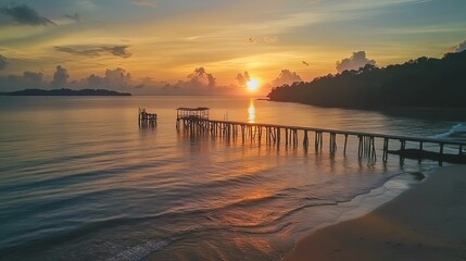 Naklejka premium A view of a fiery sunrise over an old jetty at Tanjung Langsat beach in Johor. This image may feature noise and blurry clouds from long exposure, along with soft focus and low lighting.