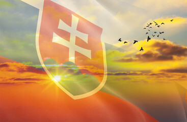 Waving the flag of Slovakia against the background of a sunset or sunrise. Slovakia flag for Independence Day. The symbol of the state on wavy fabric.