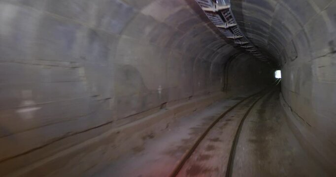 A journey through a dimly lit underground mine tunnel shows the tracks and surrounding walls, highlighting the unique environment and past mining activities.