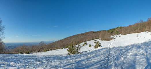 ampia vista panoramica su un ambiente naturale innevato, tra colline e montagne selvagge, nella...