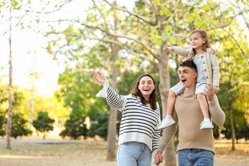 Happy family pointing at something while walking in beautiful autumn park