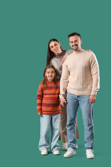 Happy family with their daughter in sweaters on green background