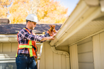 Obraz premium man with hard hat standing on steps inspecting house roof