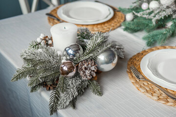 Elegant holiday table centerpiece with candle and ornaments in a cozy setting
