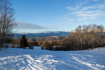 ampia vista panoramica di un ambiente che si estende tra le colline e le montagne innevate slovene,...