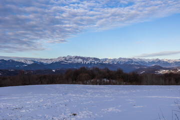 ampia vista panoramica di un ambiente che si estende tra le colline e le montagne innevate slovene,...