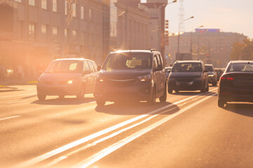 Autumn landscape and view of the road with cars. Orange evening sun and reflections on cars.