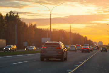Autumn landscape and view of the road with cars. Orange evening sun and reflections on cars.