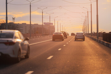 Autumn landscape and view of the road with cars. Orange evening sun and reflections on cars.