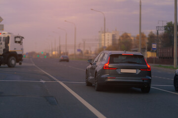 Fototapeta premium Autumn landscape and view of the road with cars. Orange evening sun and reflections on cars.