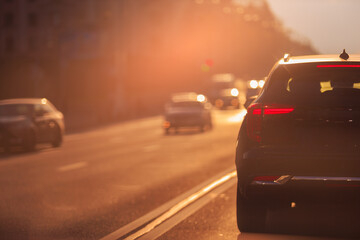 Fototapeta premium Autumn landscape and view of the road with cars. Orange evening sun and reflections on cars.