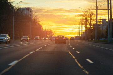 Autumn landscape and view of the road with cars. Orange evening sun and reflections on cars.