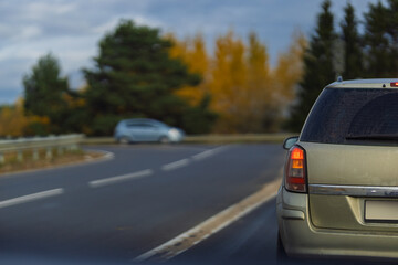 Autumn landscape and view of the road with cars. Orange evening sun and reflections on cars.