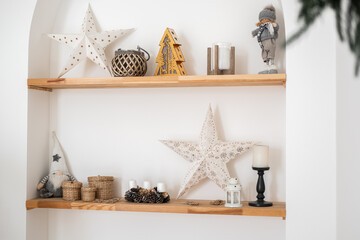 Decorative winter shelf with stars, candles, and festive ornaments in cozy space