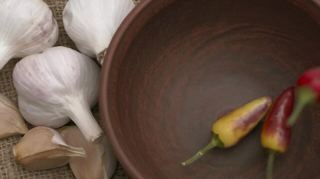 A bowl filled with fresh garlic and an array of colorful peppers, beautifully rustic in style
