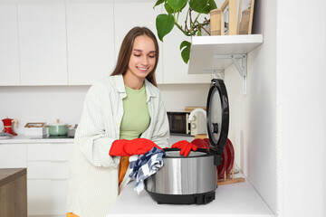 Young woman cleaning multi cooker in kitchen