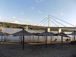 Fototapeta premium Parasols by the river with a bridge in the background.