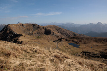 vista panoramica, in alta quota, su di un ambiente naturale di montagna nel nord Italia con tante catene montuose che si estendono verso l'orizzonte, di giorno, in autunno, avvolto dalla foschia