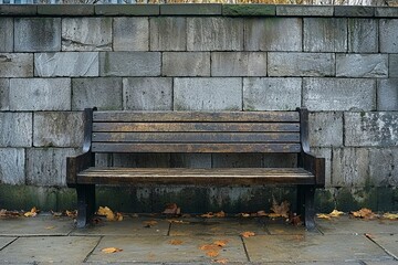 A Wooden Bench Against a Stone Wall with Fallen Autumn Leaves