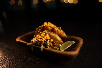 Taco with lime and vegetables in a plate on a black background.Mexican cuisine concept