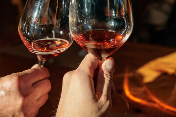 dettaglio delle mani di due uomini adulti, caucasici ed irriconoscibili mentre tengono in mano un calice ciascuno e fanno un brindisi, riempiti con una qualche bevanda, di giorno, a pranzo