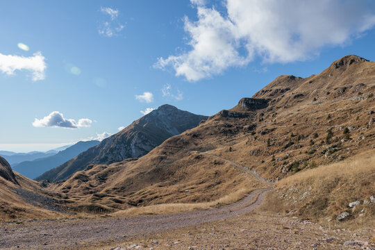vista panoramica su un ambiente di montagna in alta quota nel nord Italia, con pendii erbosi che si estendono in lontananza, sotto un cielo azzurro, di giorno, in autunno