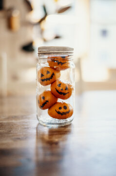 A glass jar holds clementines decorated as Halloween jack-o&rsquo;-lanterns, adding a festive seasonal touch...Europe, 31.10.2024.