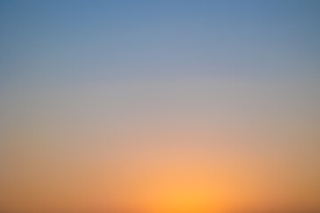 immagine sfuocata del cielo sereno al tramonto, con un gradiente che va dal colore azzurro all'arancione