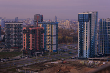 Evening view of the city. Sunset orange sky and beautiful cityscape, buildings and city streets,...