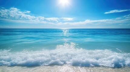 Clear blue ocean with gentle waves, sunlight creating a shimmering effect over the water