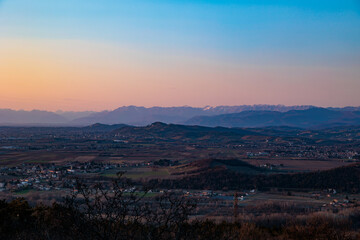 Fototapeta premium vista di parte del territorio della regione Friuli Venezia Giulia che si estende dai paesi vicino a Gorizia fino alle Alpi Giulie lontane, al tramonto, in autunno