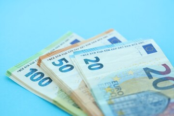 Big amount of one hundred, twenty and fifty euro money bills on blue background