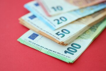 Big amount of one hundred, twenty, ten and fifty euro money bills on red background