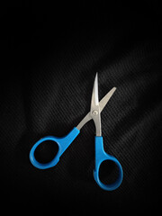 a broken small blue eyebrow scissors  on a black background 