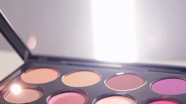 Close-up video of a makeup palette with pink and peach tones, tweezers are visible above