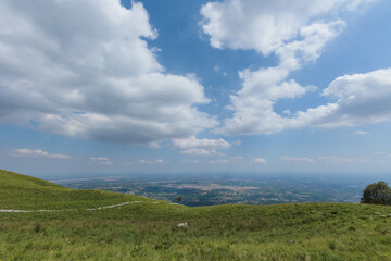 Fototapeta premium ampia panoramica con vista dai prati sulle alture di Piancavallo verso la vasta pianura del Pordenonese, nel Friuli Venezia Giulia occidentale, in estate, di giorno