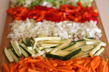 Chopped leek, red pepper, onion, zucchini and carrot on the chopping board. Cooking and meal prepping at home. Selective focus.