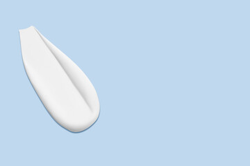 Smear of white cosmetic cream on a light blue background. Skincare product, smooth texture.