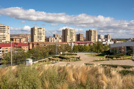 A sprawling urban skyline dotted with high-rise apartment blocks, a view that merges urban architecture with lush greenery reflecting vibrant city life in Logrono Spain