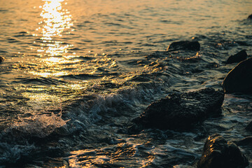 vista dettagliata delle piccole onde di marea di un mare tranquillo che bagnano la costa e le rocce al tramonto