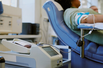 Individual sitting in a comfortable chair while donating blood in a medical facility with advanced equipment and bright surroundings