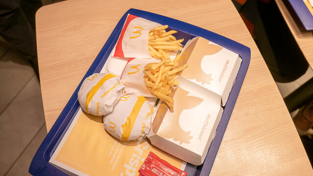 Top view of Mcdonald's meal tray with burgers, Mcchicken sandwiches, french fries, and ketchup packets in a fast-food restaurant setting, no people, tray on table indoors