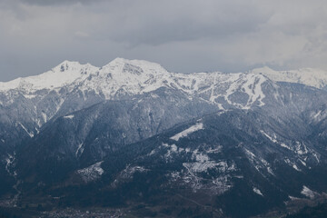 vista dettagliata di varie catene montuose lontane, completamente innevate, in un ambiente freddo e naturale di montagna nelle Alpi Italiane a nord est, sotto un cielo nuvoloso, in inverno