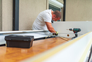 Carpenter assembling furniture using cordless screwdriver in apartment