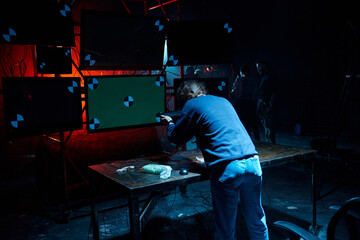 Behind the scene. Filmmaker working with professional camera in dark studio